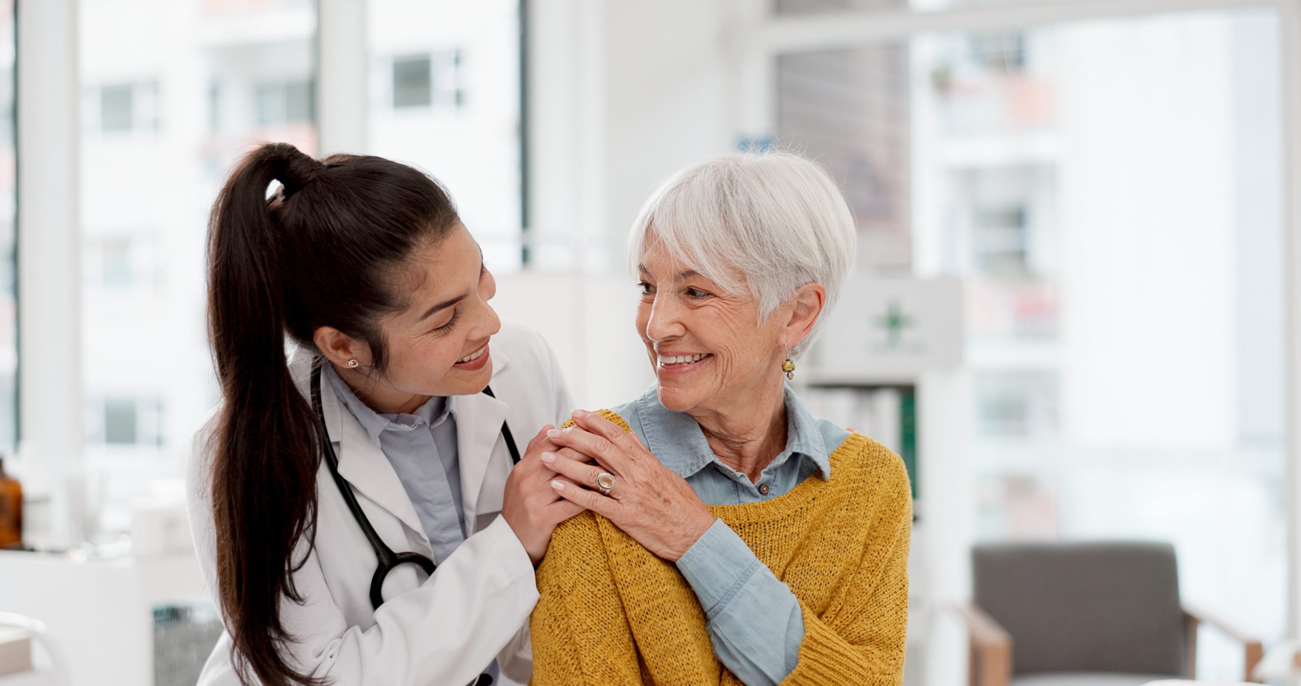 Happy, hug and face of a doctor with a woman for medical trust, healthcare and help. Laughing, care and portrait of a young nurse with a senior patient and love during a consultation at a clinic